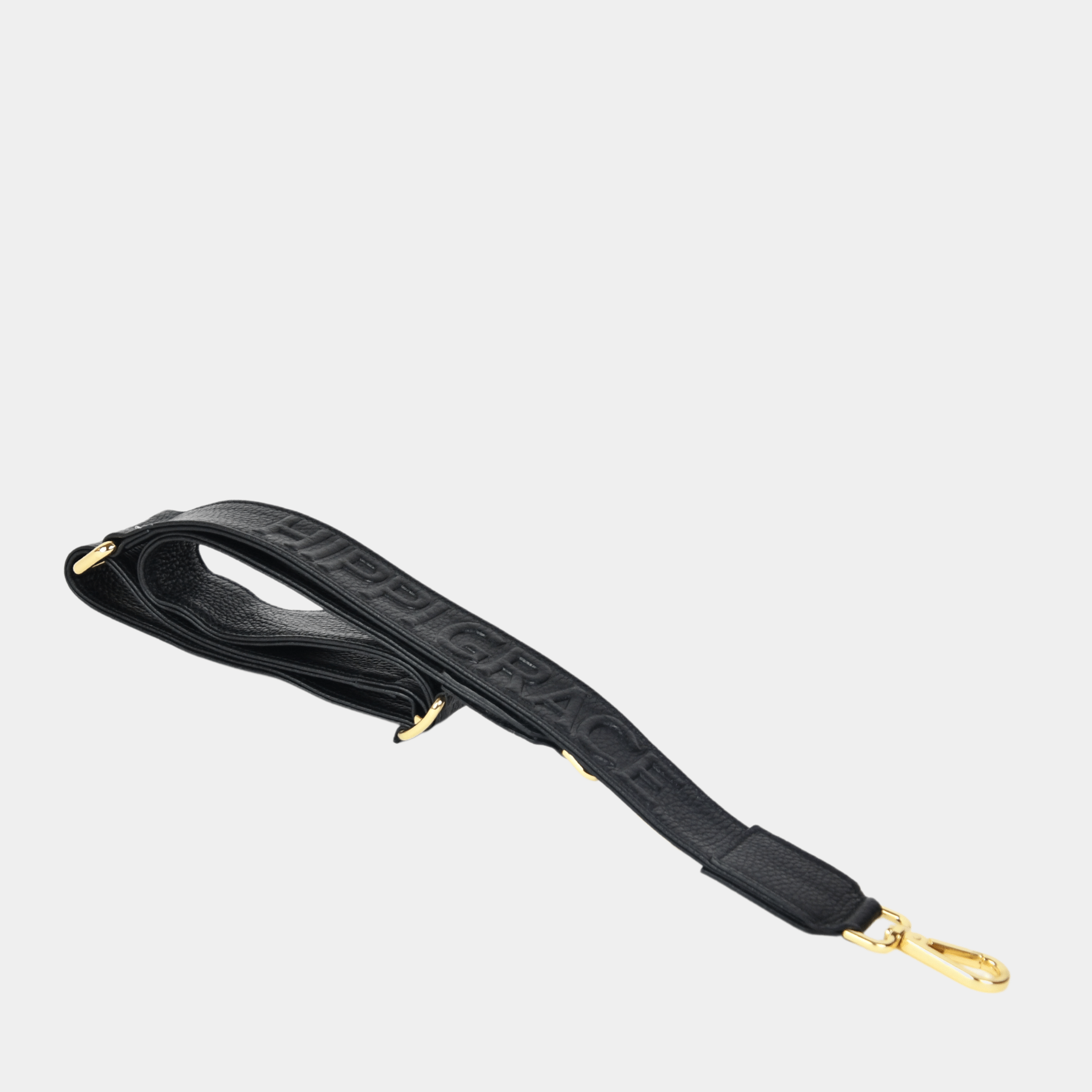 Bred skulderstropp i klassisk Ku-skinn, Crossbody lengde, Preget Logo, gull detaljer. Hippi Grace Preget Regulerbar Stropp i Klassisk Sort med Gull. Ekte skinn. Skinnstropp til veske i ekte skinn. Norsk Design.
