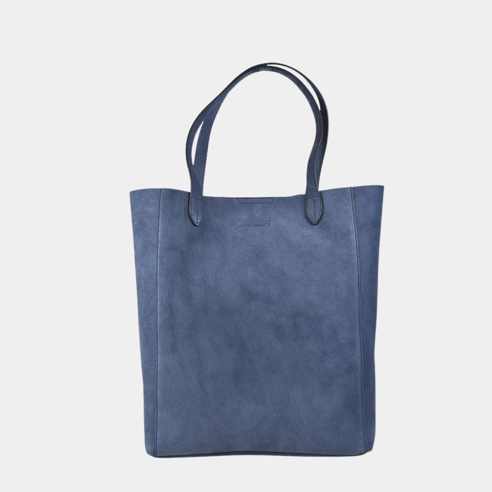 Tote veske i lekkert lyse brunt skinn fra Hippi Grace. Tote vesken Stockholm i fargen nobuck jeansblå fra Hippi Grace er en stor skinnveske til dame. Skulder vesken passer perfekt som jobbveske, skoleveske, reiseveske og hverdagsveske. Vesken har et stilrent design, med et romslig interiør. Vesken lukkes med en metallknapp i topp. Skinnveske dame. Blå tote bag i ekte skinn. Blå skulderveske i ekte skinn. Norsk design.