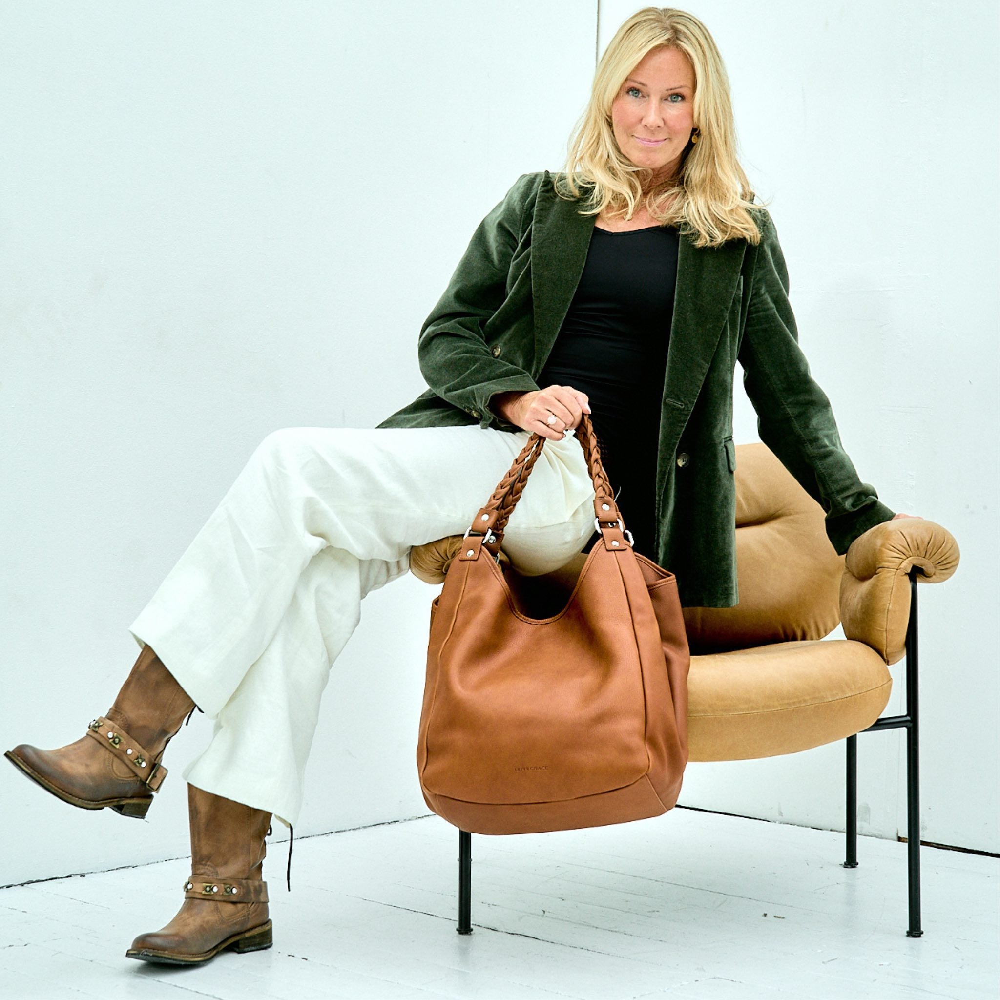 Hippi Grace Bergen New i fargen bohem luxe tan. Stor veske til dame i ekte skinn. Stor skinnveske til dame. Stor skulderveske til dame. Jobbveske dame i lys brun. Skinnveske i klassisk brun. Brun jobbveske til dame. Vesken har flettede skulderstropper med gulldetaljer. Den har et romslig hovedrom med glidelås lukking i topp. bag. veske dame i ekte skinn. norsk design. Her ser du vesken på en modell