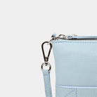 Liten veske i klassisk Ku-skinn med glidelås-lukning, lang skulderstropp og håndleddsstropp. Skinn veske. veske dame. bag. norsk design. lyseblå veske i ekte skinn. Hippi Grace 3in1 i fargen bohem lyseblå.  I dette bildet ser du et nærbilde av detaljene på vesken.[wv]