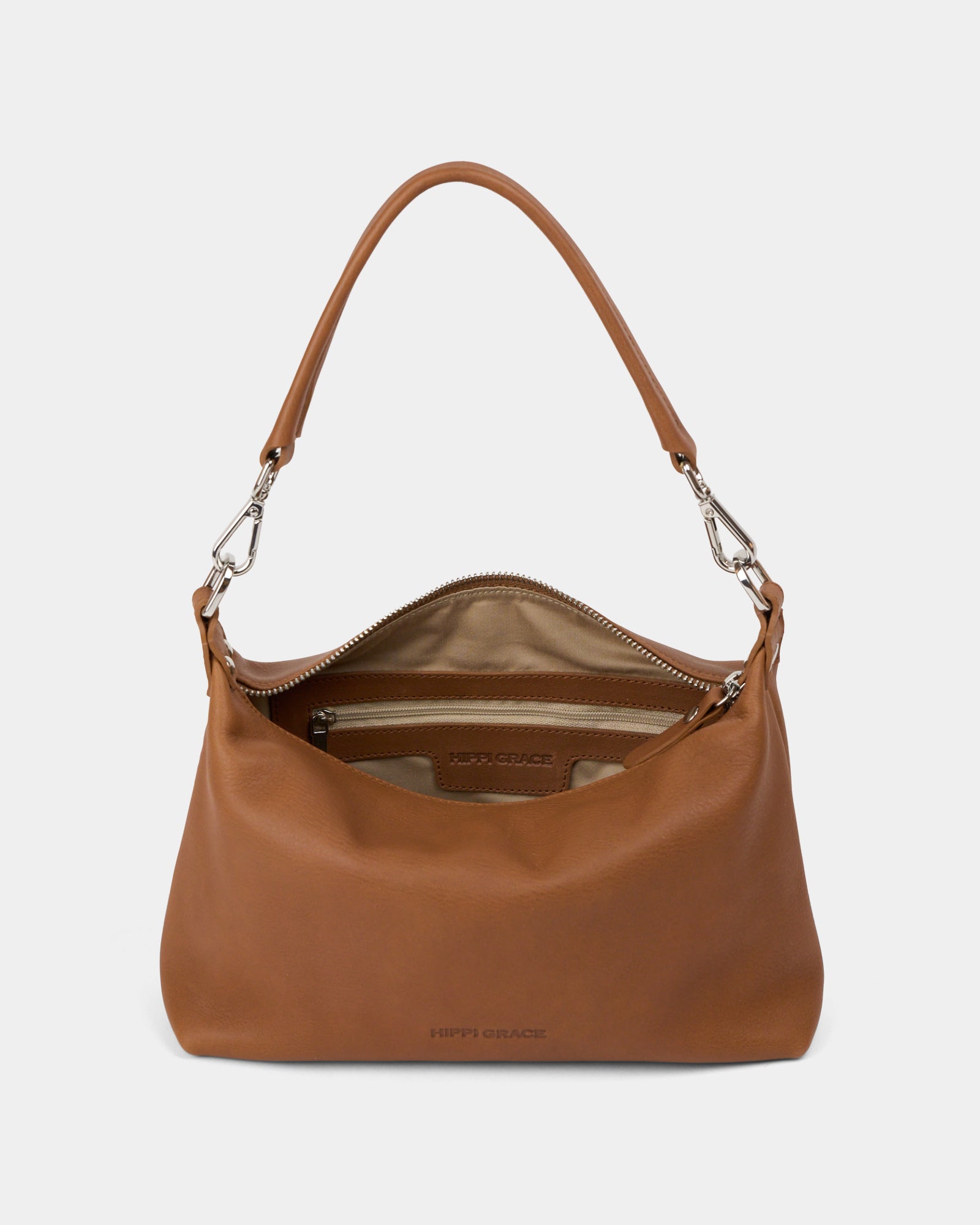 Hippi Grace Lucca i fargen bohem luxe tan er en liten skinnveske til dame. Vesken har et minimalistisk og tidløst design, og har et praktisk interiør med glidelås lukking i topp. Skinnvesken kommer med en skulderstropp og en regulerbar crossbody stropp, begge avtagnbare. Norsk Design. Lysebrun skinnveske dame. Brun Veske dame. Hverdagsveske. Festveske. Ekte skinn. Bærekraftig. Skulderveske dame. Crossbody veske dame. Crossbodyveske. Små veske. Mindre veske. Bilde av vesken foran. [wv]