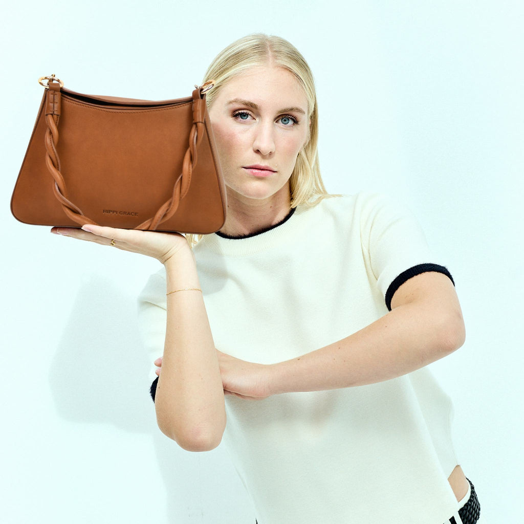 Hippi Grace Paris i fargen bohem luxe tan er en liten skinnveske til dame. Vesken kommer med en flettet skulderstropp og en regulerbar crossbody stropp, begge avtagbare. Skuldervesken passer perfekt som både hverdagsveske og festveske. Vesken har en dobbel lukking med magnet knapp i topp. Crossbody vesken har et elegant design, med inspirasjon fra den franske baguette vesken. Norsk design. Lysebrun Skinnveske dame. Lysebrun veske i skinn. Festveske dame. Baguette bag i ekte skinn. 