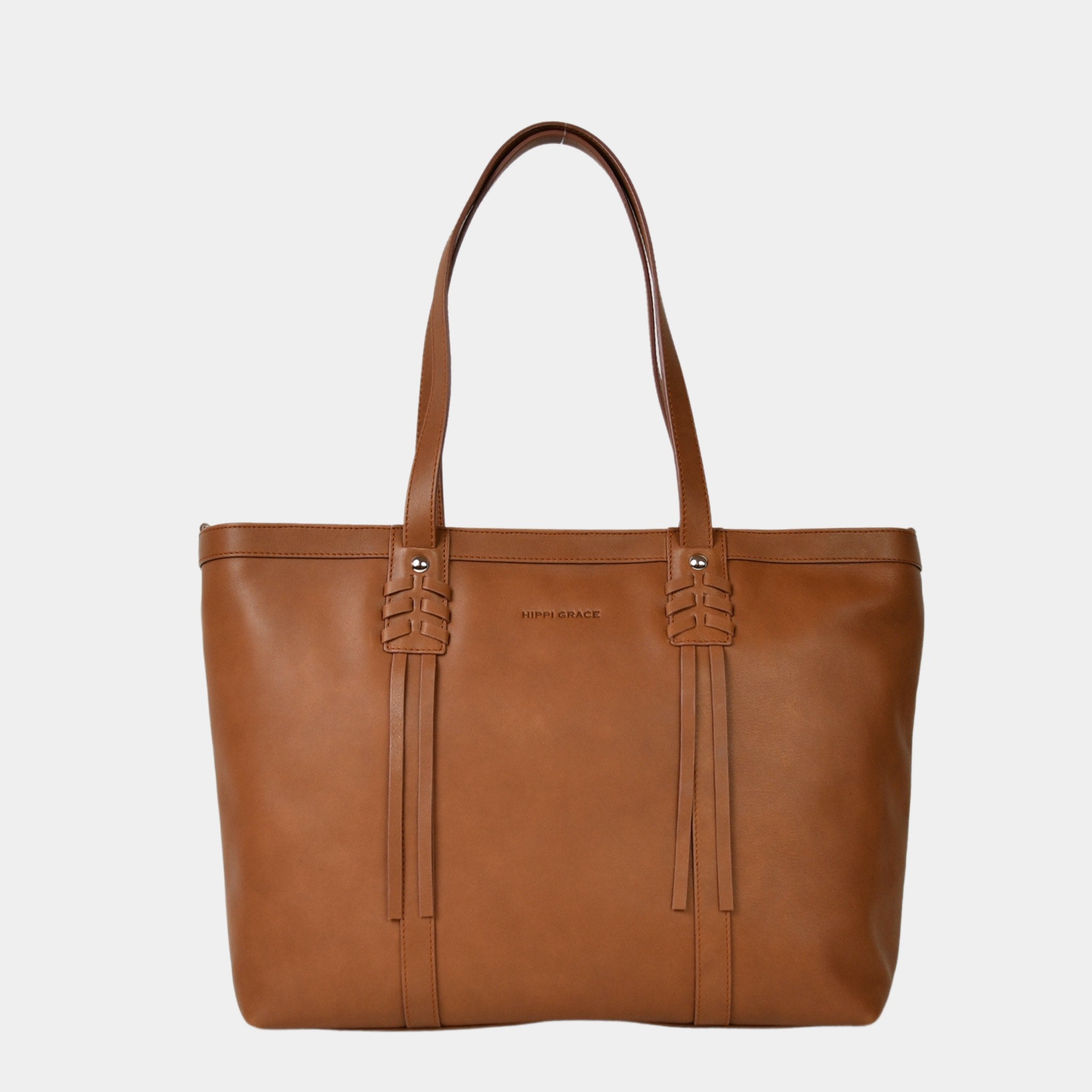 Hippi Grace Ibiza i fargen bohem luxe tan er en stor tote veske til dame i ekte skinn. Den har et praktisk og romslig interiør med flere lommer og glidelås lukking i topp. Den har pene frynse detaljer i front, og lange skulderremmer. Ibiza har et unikt og tidløst design du aldri går lei av. Skinnvesken er perfekt til jobb, skole, reise og hverdag. Norsk design. Stor veske dame. Stor Skulderveske i ekte skinn. Tote bag