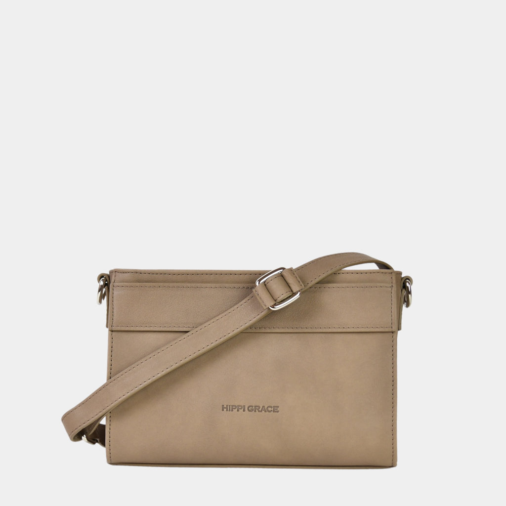 Hippi Grace Kyoto er en liten skinnveske til dame i fargen bohem luxe Beige. Vesken kommer med en regulerbar og avtagbar crossbody stropp. Beige crossbody småveske i ku-skinn. Hverdagsveske i ekte skinn. Festveske i ekte skinn. Norsk design. Glidelås lukking i topp. Beige skinnveske. Skinnveske i Beige. Beige veske i ekte skinn. Crossbody veske i ekte skinn.