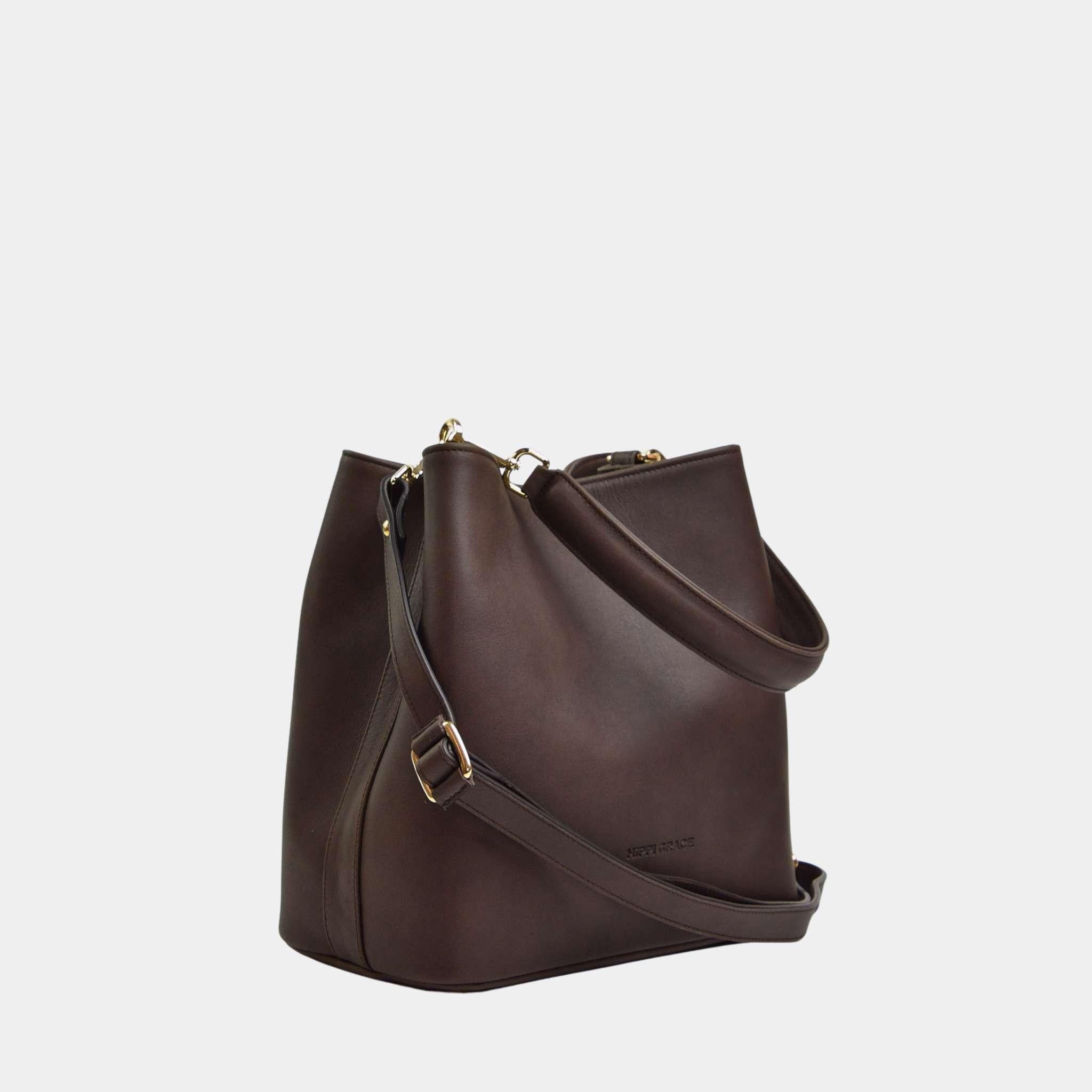 Hippi Grace Marbella i Bohem Luxe Mocca med Gulldetaljer er en mellomstor skinnveske til dame. Vesken kommer med en skulderstropp og en regulerbar crossbody stropp, begge avtagbare. Vesken har et rent og elegant design, med et praktisk interiør. Veskens interiør har to hovedrom og flere små lommer, med magnet lukking i topp. Mørkebrun skulderveske dame. Mørkebrun Crossbody veske. Brun skinnveske. Norsk design. Bucket Bag i ekte skinn. [wv]