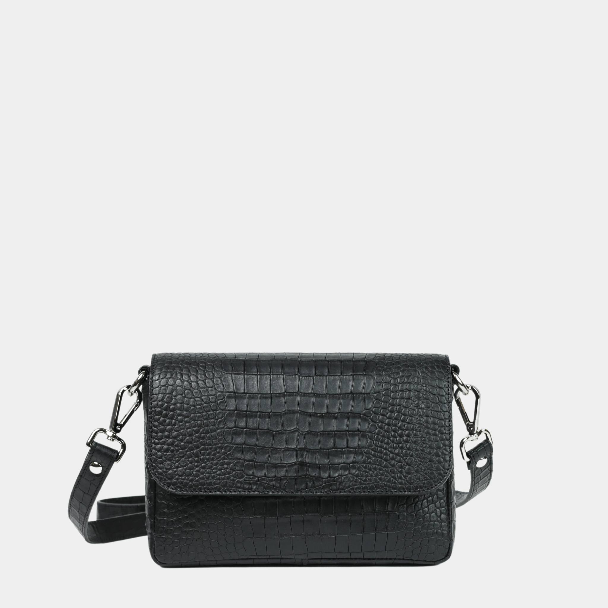 Liten veske, Ku-skinn, magnet-lås, crossbody skulderstropp, sølvdetaljer. Hippi Grace Monte Carlo i fargen coco sort er en liten skinnveske til dame. Vesken kommer med en regulerbar crossbody stropp, avtagbar. Vesken har et stilrent og praktisk design, med magnet lås i front. Svart Crossbody veske i ekte skinn. Svart veske dame. Skulderveske svart. Norsk design. 