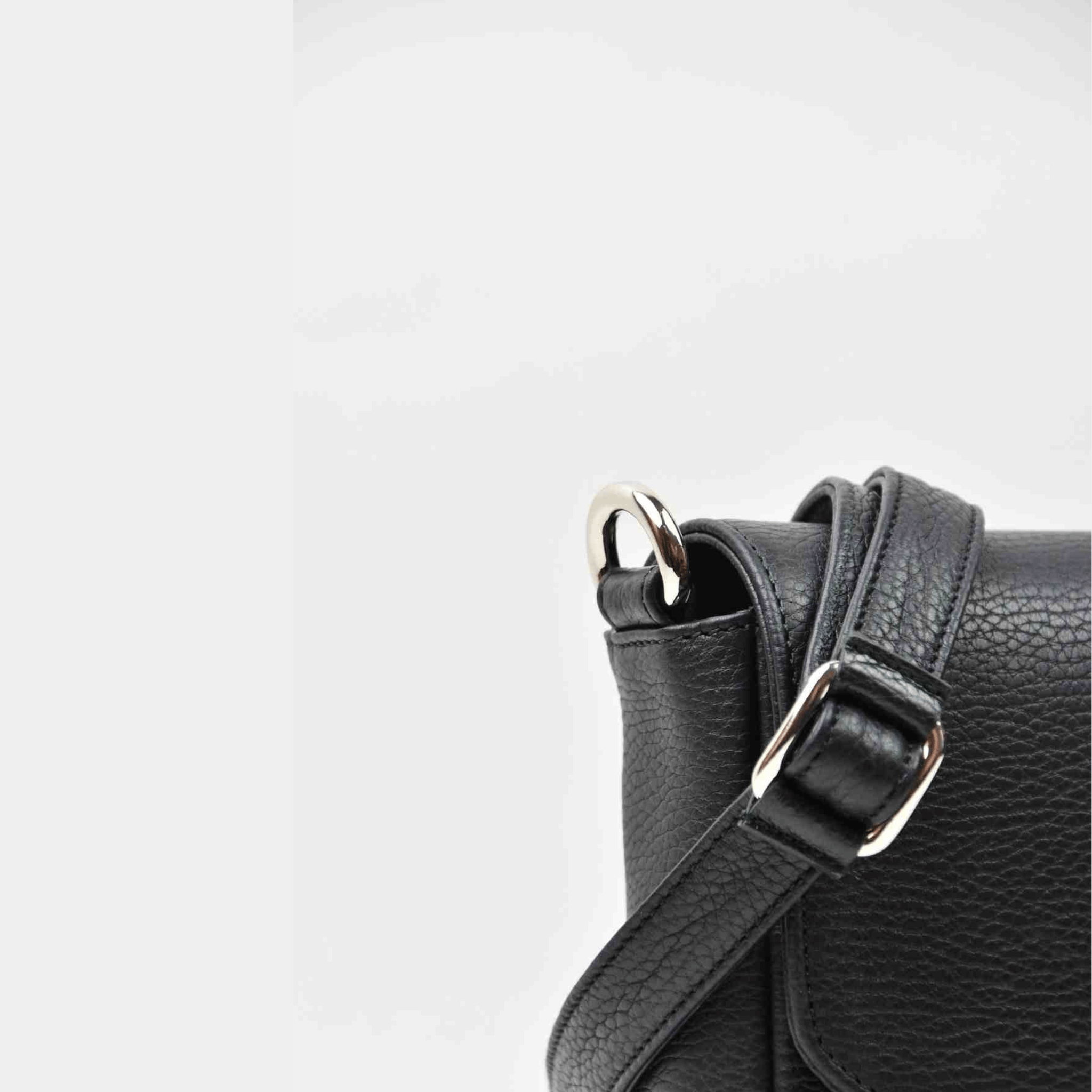 Liten veske, Ku-skinn, magnet-lås, crossbody skulderstropp, sølvdetaljer. Hippi Grace Monte Carlo i fargen klassisk sort er en liten skinnveske til dame. Vesken kommer med en regulerbar crossbody stropp, avtagbar. Vesken har et stilrent og praktisk design, med magnet lås i front. Svart Crossbody veske i ekte skinn. Svart veske dame. Skulderveske svart. Norsk design. Bilde av baksiden til vesken. Nærbilde av veskens detaljer. [wv]
