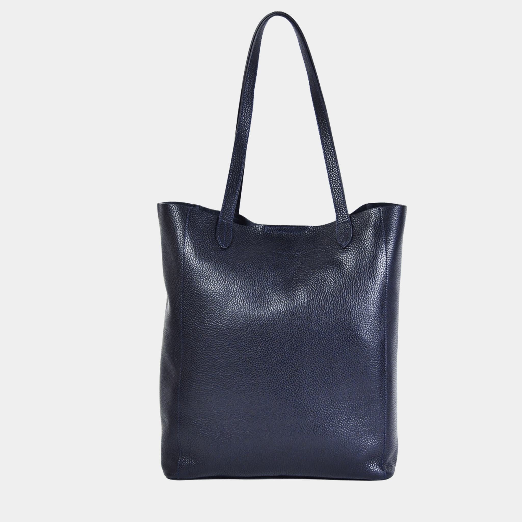 Tote veske i lekkert mørkeblå skinn fra Hippi Grace. Tote vesken Stockholm i fargen klassisk mørkeblå fra Hippi Grace er en stor skinnveske til dame. Skulder vesken passer perfekt som jobbveske, skoleveske, reiseveske og hverdagsveske. Vesken har et stilrent design, med et romslig interiør. Vesken lukkes med en metallknapp i topp. Skinnveske dame. Marineblå tote bag i ekte skinn. Mørkeblå skulderveske i ekte skinn. Norsk design.