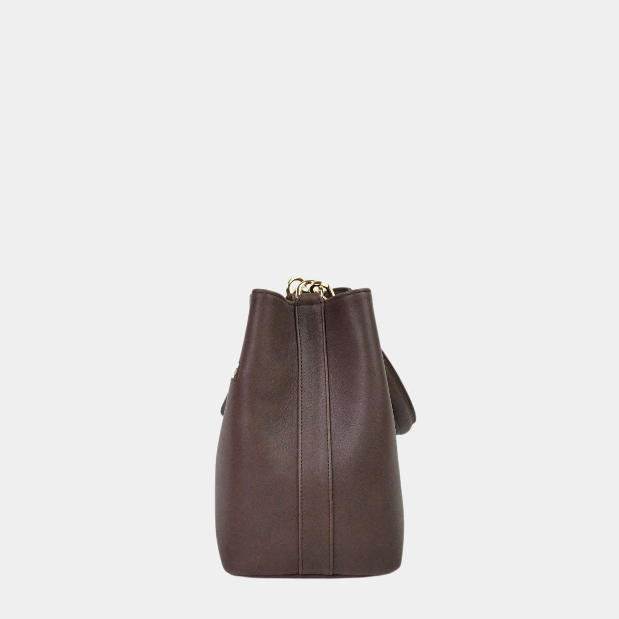 Hippi Grace Marbella i Bohem Luxe Mocca med Gulldetaljer er en mellomstor skinnveske til dame. Vesken kommer med en skulderstropp og en regulerbar crossbody stropp, begge avtagbare. Vesken har et rent og elegant design, med et praktisk interiør. Veskens interiør har to hovedrom og flere små lommer, med magnet lukking i topp. Mørkebrun skulderveske dame. Mørkebrun Crossbody veske. Brun skinnveske. Norsk design. Bucket Bag i ekte skinn. Siden av vesken. [wv]