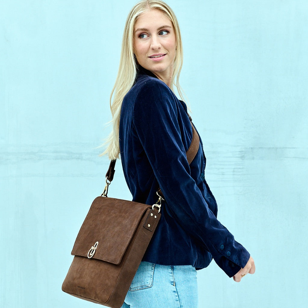 Crossbody veske, Klassisk Ku-skinn, Skulder og crossbody stropp, gulldetaljer. Hippi Grace Tokyo i fargen Nobuck Mocca er en stor skinnveske til dame. Vesken kommer med en regulerbar crossbody stropp som også er avtagbar. Crossbody vesken har et lekkert design med en gullås i front. Skuldervesken har et praktisk interiør, og passer perfekt som Jobbveske, skoleveske, hverdagsveske og reiseveske. Norsk design. Mørkebrun skinnveske dame. Jobbveske i ekte skinn.