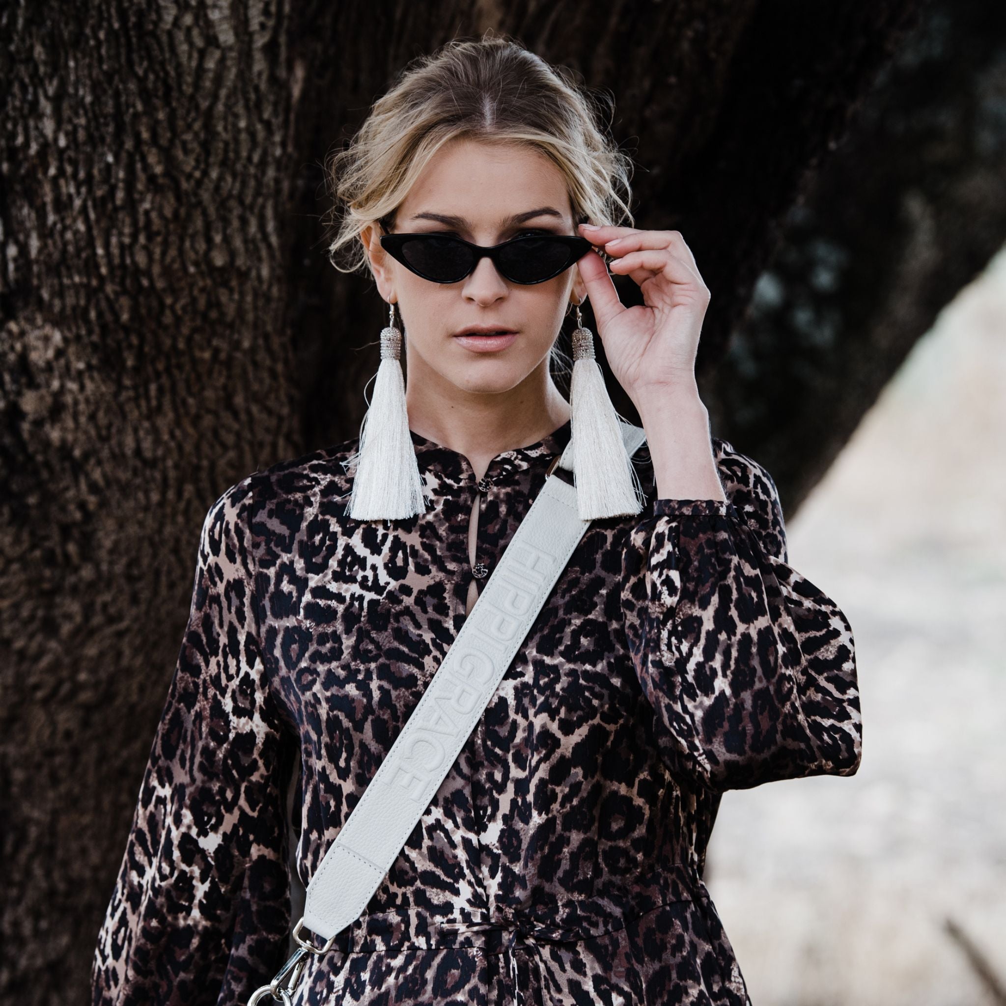 [wv] Bred skulderstropp i klassisk Ku-skinn, Crossbody lengde, Preget Logo.  Hippi Grace Preget Stropp i Klassisk Offwhite. Ekte skinn. Skinnstropp til veske i ekte skinn. Norsk Design. Bilde på modell. 