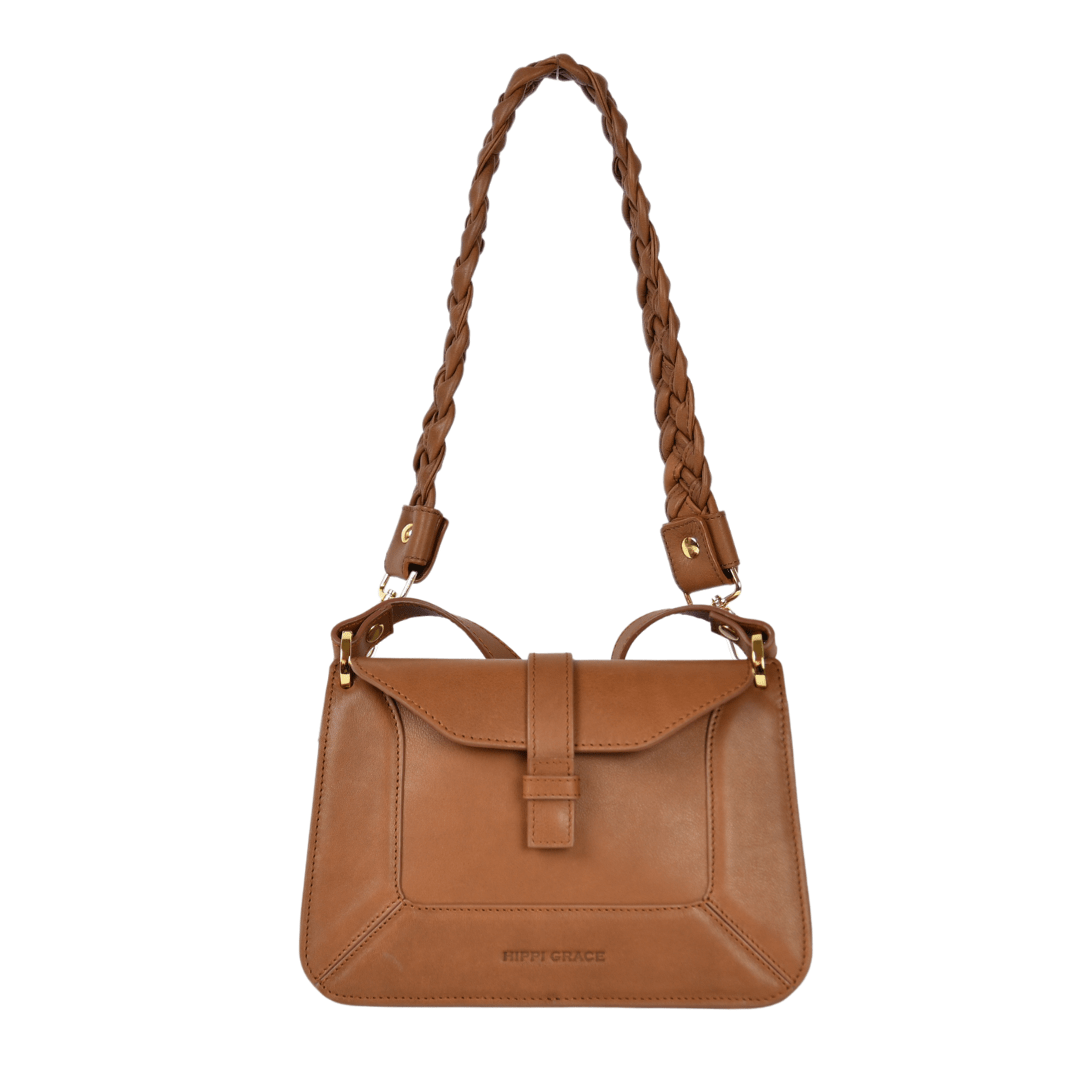 Hippi Grace Lille Roma i fargen bohem luxe tan er en liten skinnveske til dame. Vesken kommer med en lang crossbody stropp, som er regulerbar og avtagbar. Vesken har nydelige detaljer, og gullfarget metall. Crossbody vesken har et praktisk interiør med flere lommer, og lukkes med en magnetknapp i front. Norsk design. Vesken er perfekt til både reise og fest. Brun liten skinnveske dame. Lysebrun liten veske i skinn. Bilde av Lille Roma med en flettet rund skulderstropp i fargen bohem luxe tan. [wv]