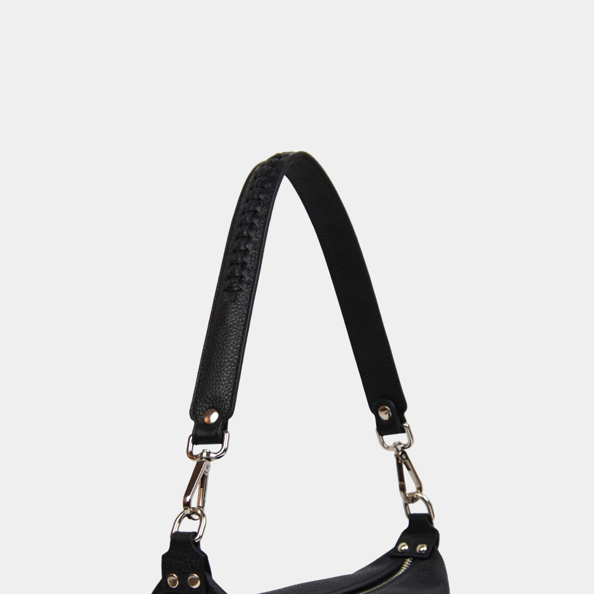 Skulderstropp med flettemønster i sort skinn med sølvfargede spenner. [wv]