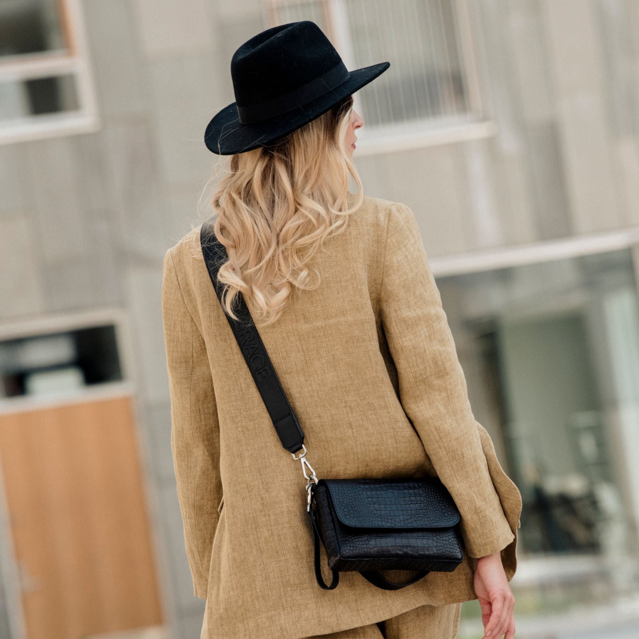 Liten veske, Ku-skinn, magnet-lås, crossbody skulderstropp, sølvdetaljer. Hippi Grace Monte Carlo i fargen coco sort er en liten skinnveske til dame. Vesken kommer med en regulerbar crossbody stropp, avtagbar. Vesken har et stilrent og praktisk design, med magnet lås i front. Svart Crossbody veske i ekte skinn. Svart veske dame. Skulderveske svart. Norsk design. Bilde av vesken på en model. [wv]