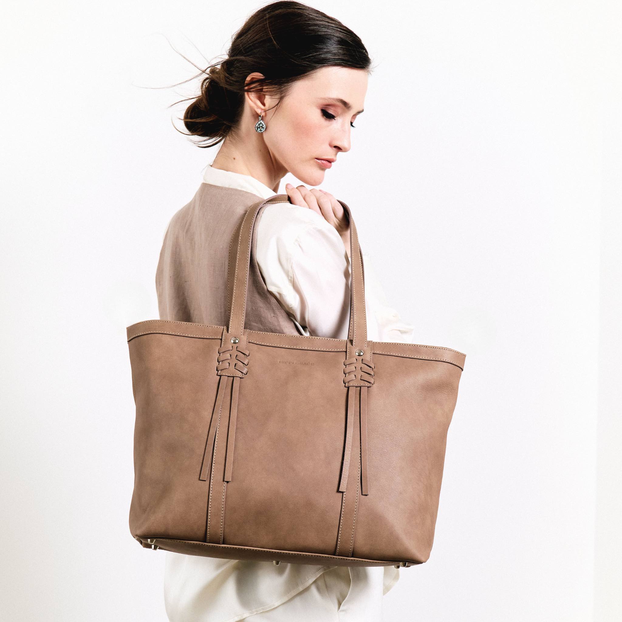 Hippi Grace Ibiza i fargen bohem luxe beige er en stor tote veske til dame i ekte skinn. Den har et praktisk og romslig interiør med flere lommer og glidelås lukking i topp. Den har pene frynse detaljer i front, og lange skulderremmer. Ibiza har et unikt og tidløst design du aldri går lei av. Skinnvesken er perfekt til jobb, skole, reise og hverdag. Norsk design. Stor veske dame. Stor Skulderveske i ekte skinn. Tote bag med sølvdetaljer. Bilde av vesken på en model. [wv]