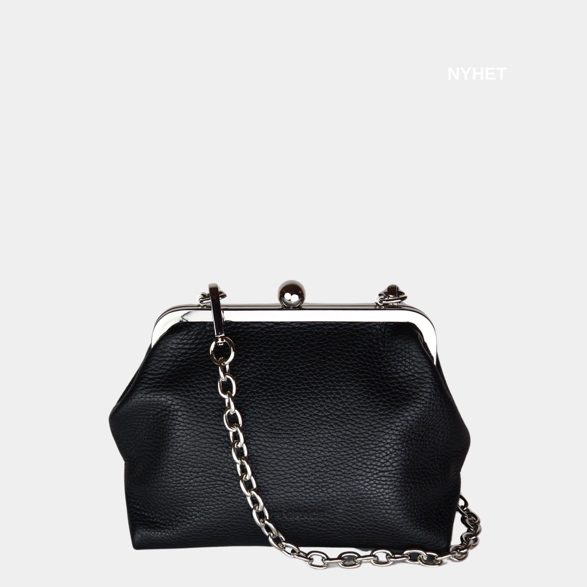 Hippi Grace Positano i fargen Klassisk Sort er en liten skinnveske til dame i Norsk Design. Vesken er laget av nydelig ekte skinn, og har lekre sølv detaljer og klikk lås i topp. Selskapsvesken kommer med en lekker metall chain som stropp og en regulerbar Crossbody Stropp, begge avtagbare. . Denne festvesken har et unikt design og et smart interiør. Et smykke til din garderobe. Svart veske i ekte skinn. Veske i Skinn. Svart Skinnveske Dame. Modellbilde av Positano