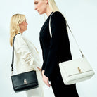 Hippi Grace Hanoi i fargene klassisk sort og Bohem Luxe Ivory med gulldetaljer er en mellomstor veske til dame i ekte skinn. Skinnvesken kommer med en regulerbar crossbody stropp og har et praktisk interiør med flere lommer. Vesken har en gullås i front som legger til en fin detalj. Legg til en skulderstropp for en ekstra detalj og for å bære den som en skulderveske. Norsk design. Liten veske dame. Svart veske. Mellomstor veske dame. Crossbody veske i ekte skinn. Modell Bilde [wv]