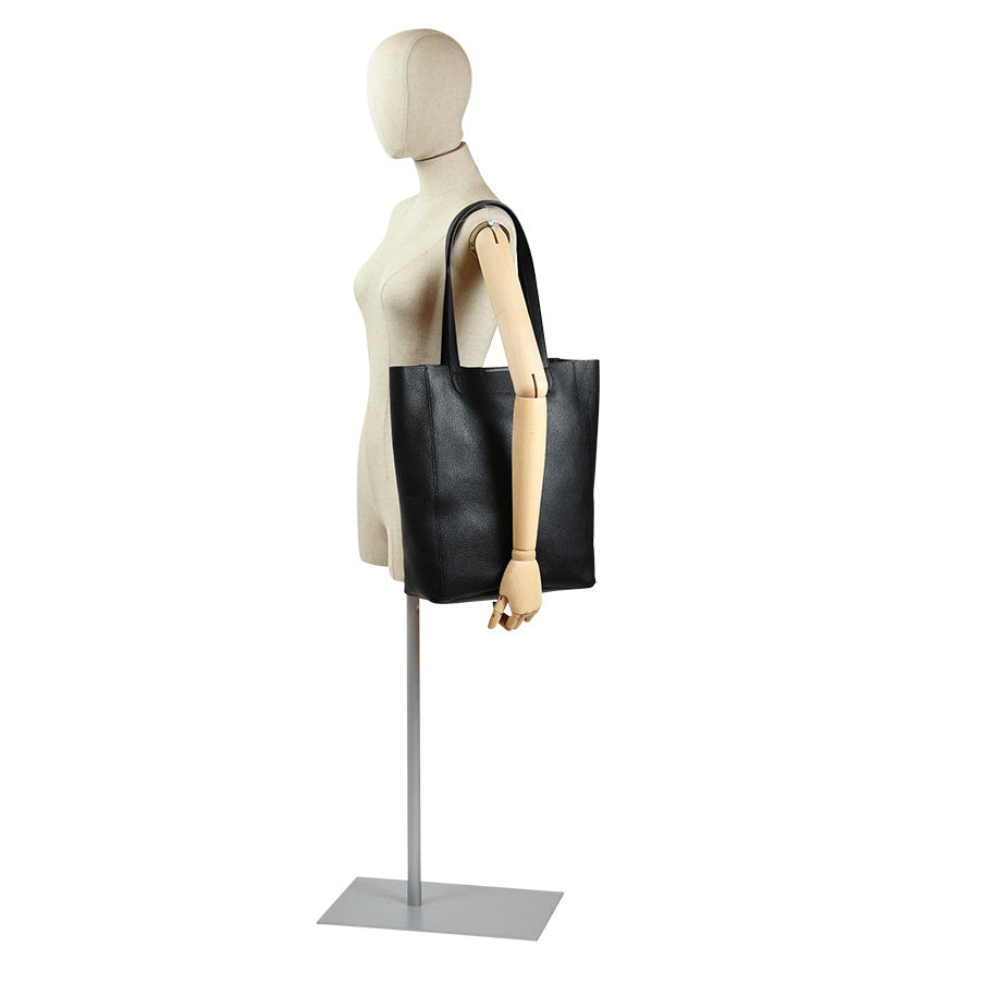 Sort skulderveske, tote bag i ku skinn på modell. Tote veske i lekkert svart skinn fra Hippi Grace. Tote vesken Stockholm i fargen klassisk sort fra Hippi Grace er en stor skinnveske til dame. Skulder vesken passer perfekt som jobbveske, skoleveske, reiseveske og hverdagsveske. Vesken har et stilrent design, med et romslig interiør. Vesken lukkes med en metallknapp i topp. Skinnveske dame. Svart tote bag i ekte skinn. Svart skulderveske i ekte skinn. Norsk design. [wv]